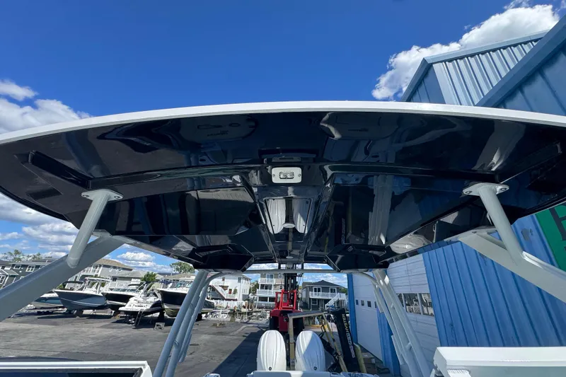 Slide: The Image of 2026 Stingray 259 DC boat with sleek black canopy, docked under clear blue sky. - 24