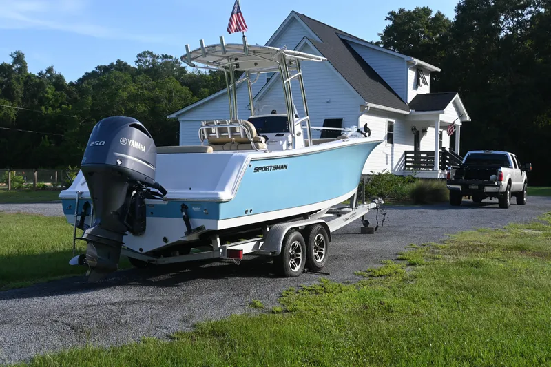 Slide: The Image of 2018 Sportsman Open 232 Center Console boat on trailer, parked near a house. - 3