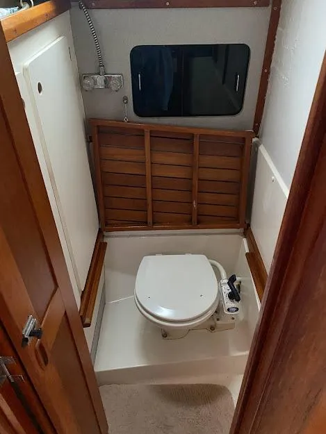 Slide: The Image of 1988 Hunter 333 boat bathroom with wooden accents and compact toilet. - 12
