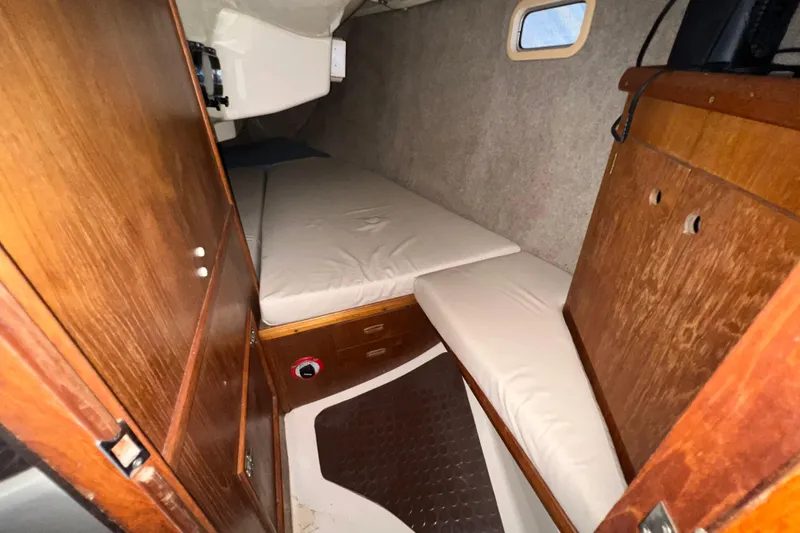 Slide: The Image of 1988 Hunter 333 sailboat cabin interior with wooden finish and cushioned seating. - 15