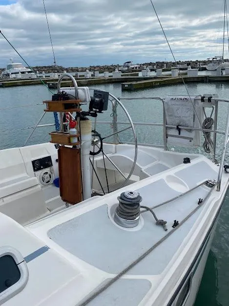 Slide: The Image of 1988 Hunter 333 sailboat cockpit with steering wheel, winch, and marina background. - 17