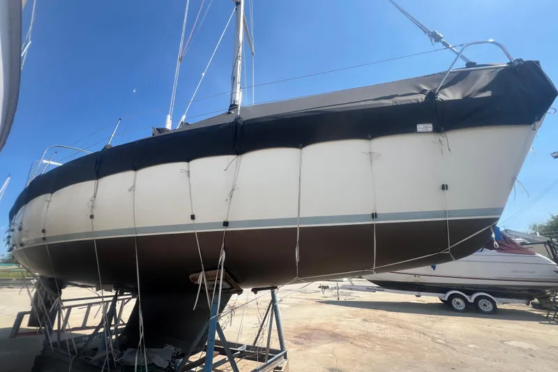 Slide: The Image of 1988 Hunter 333 sailboat on stands, covered, under clear blue sky. - 2