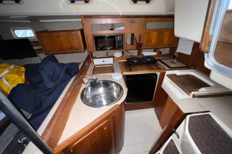Slide: The Image of Interior of 1988 Hunter 333 sailboat kitchen with sink, stove, and wooden cabinetry. - 7
