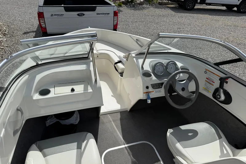 Slide: The Image of 2012 Bayliner 175 boat interior with steering wheel and dashboard, parked near a Ford truck. - 11