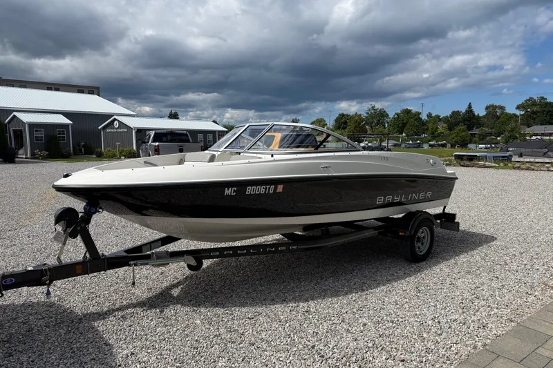 Slide: The Image of 2012 Bayliner 175 boat on trailer, parked on gravel under cloudy sky. - 7