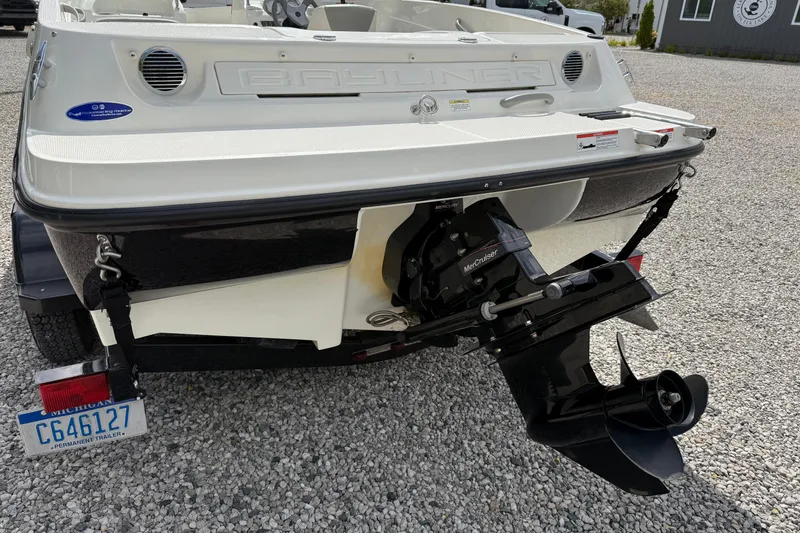 Slide: The Image of 2012 Bayliner 175 boat rear view with MerCruiser engine on gravel surface. - 20
