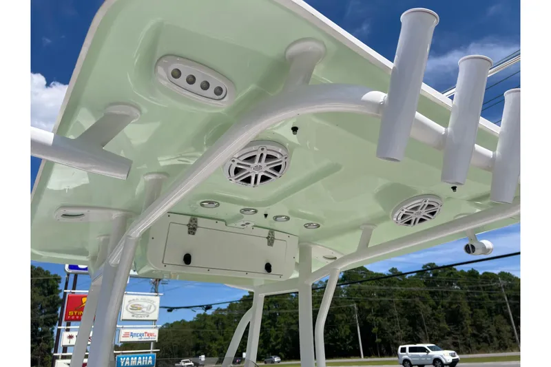 Slide: The Image of 2026 Sea Hunt Ultra 229 boat T-top with speakers and rod holders under a clear sky. - 21