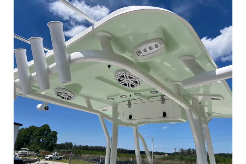 Slide: The Image of 2026 Sea Hunt Ultra 229 boat T-top with rod holders and speakers under a clear sky. - 23