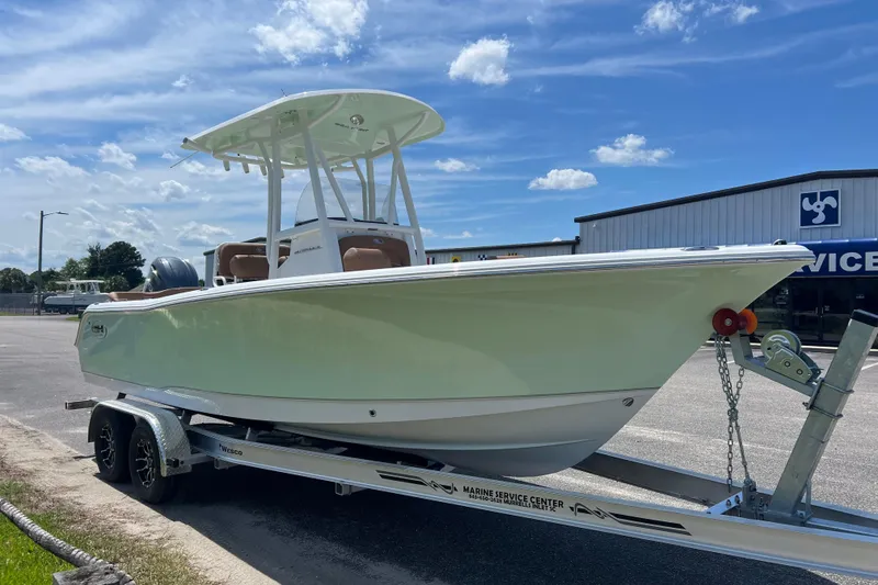 Slide: The Image of 2026 Sea Hunt Ultra 229 boat on trailer, parked outside a marine service center. - 5