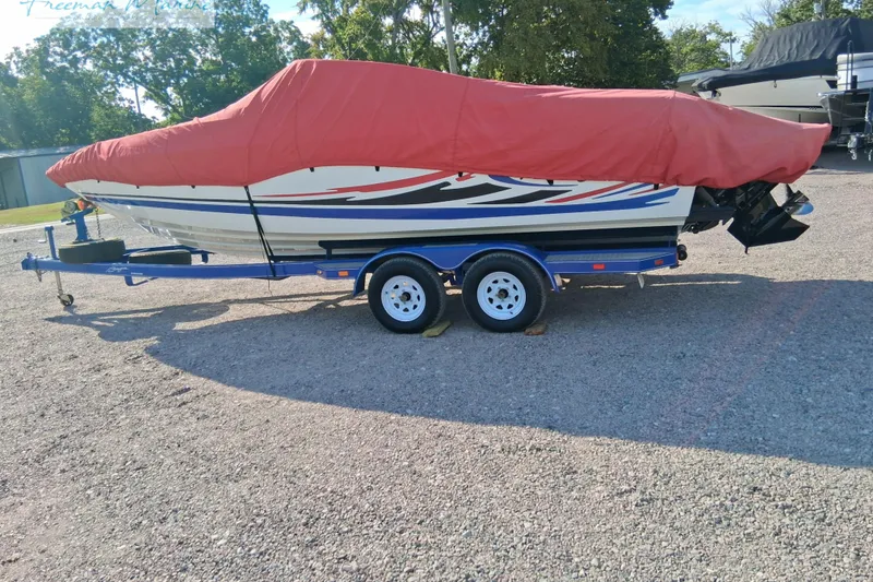 Slide: The Image of 2007 Baja 245 boat with red cover on trailer, parked outdoors. - 16