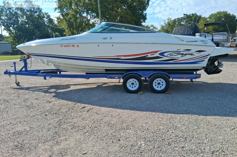 Slide: The Image of 2007 Baja 245 boat on trailer, white with red and blue graphics, parked outdoors. - 2