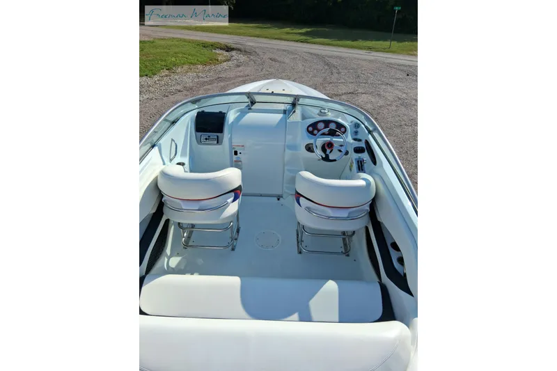 Slide: The Image of 2007 Baja 245 boat interior with white seating and dashboard, parked on gravel. - 8