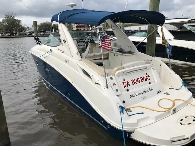 Slide: The Image of 2012 Sea Ray 280 Sundancer boat docked, featuring blue canopy and American flag. - 5