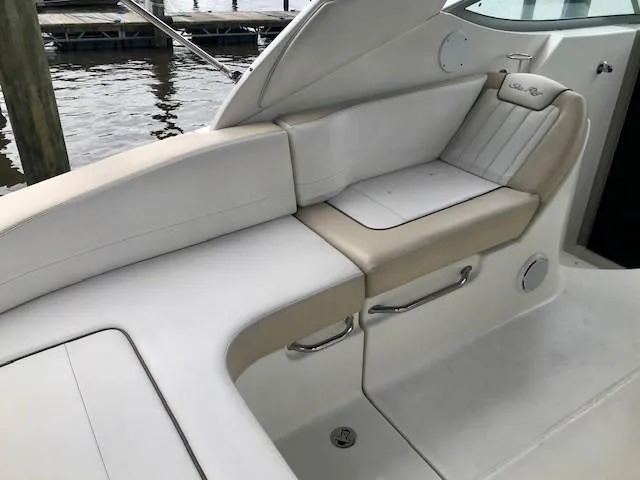 Slide: The Image of 2012 Sea Ray 280 Sundancer boat interior seating, featuring white and beige upholstery. - 7