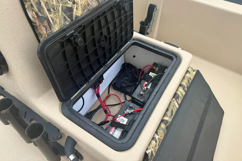 Slide: The Image of 2025 Carolina Skiff E18 JVX CC boat battery compartment with wiring and storage. - 12