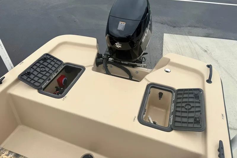 Slide: The Image of 2025 Carolina Skiff E18 JVX CC boat with open storage compartments and outboard motor. - 21