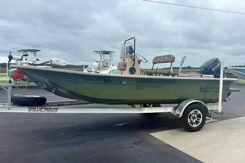 Slide: The Image of 2025 Carolina Skiff E18 JVX CC boat on trailer, parked outdoors. - 5