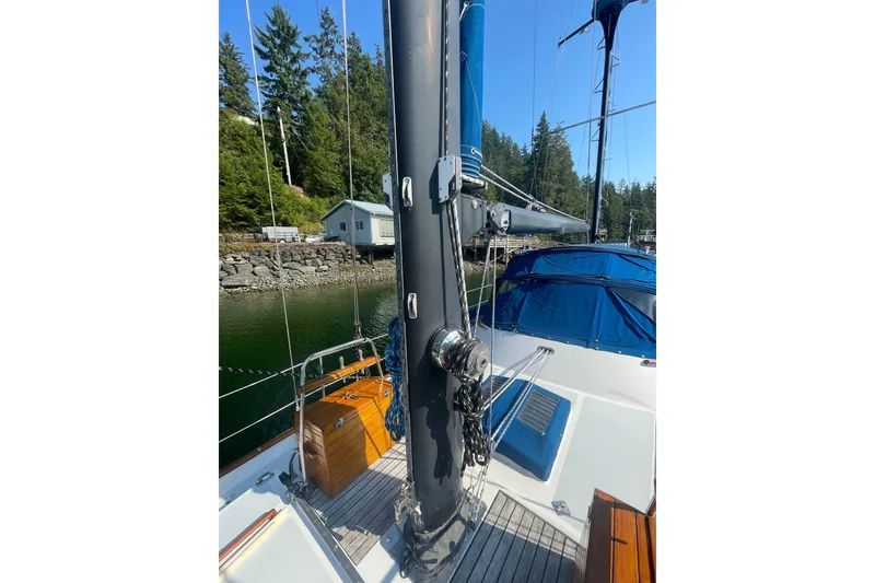 Slide: The Image of 1981 Mariner 48 sailboat deck with mast, docked near lush greenery. - 14