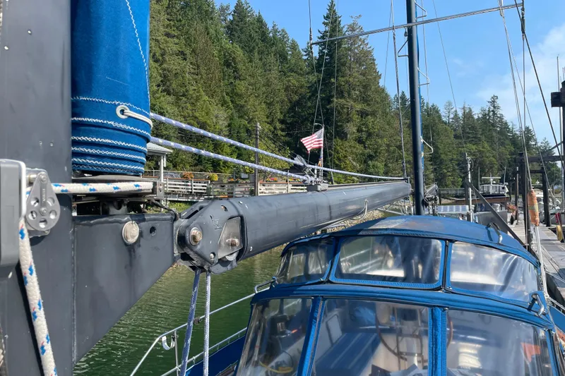 Slide: The Image of 1981 Mariner 48 sailboat docked, featuring blue canvas and rigging, with forested background. - 15