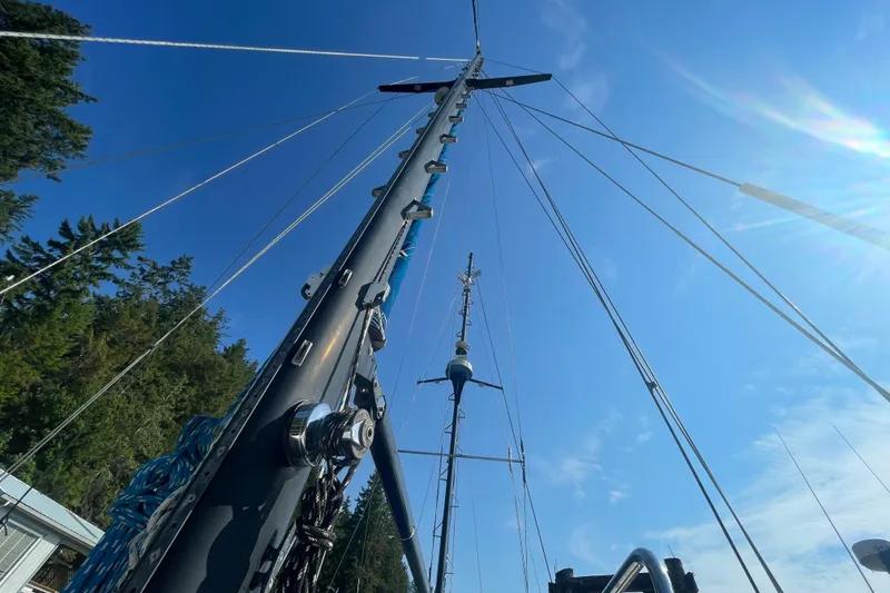 Slide: The Image of Mast of 1981 Mariner 48 sailboat against clear blue sky, surrounded by trees. - 16