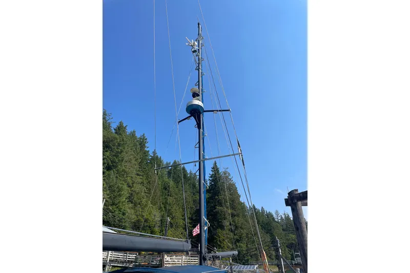Slide: The Image of 1981 Mariner 48 sailboat mast against clear blue sky and forest backdrop. - 17