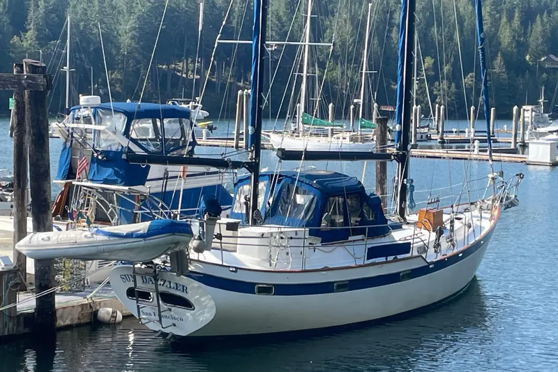 Slide: The Image of 1981 Mariner 48 sailboat docked in a serene marina with forested background. - 3