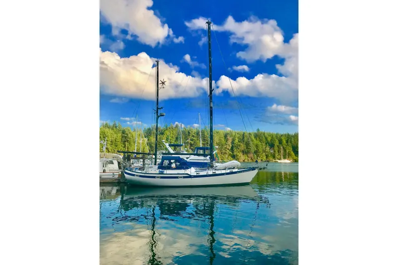 Slide: The Image of 1981 Mariner 48 sailboat docked on serene water, under a vibrant blue sky. - 45