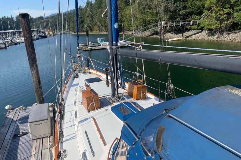 Slide: The Image of 1981 Mariner 48 sailboat docked in a serene marina with lush greenery. - 6