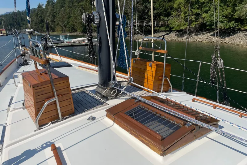 Slide: The Image of 1981 Mariner 48 sailboat deck with wooden features and rigging, docked by a forested shoreline. - 8