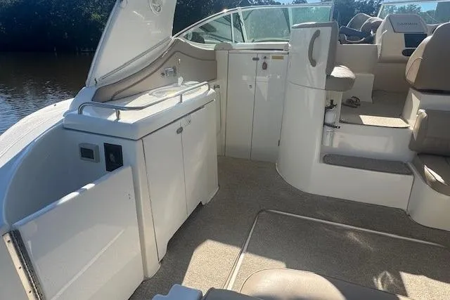 Slide: The Image of 2001 Cruisers Yachts 3672 Express interior with seating and kitchenette, docked by the water. - 10