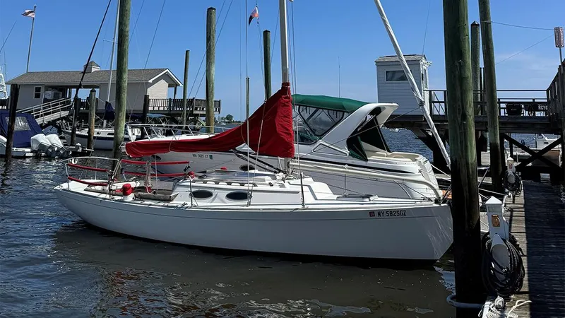 The Image of 2006 Alerion Express 28 sailboat docked at a marina with red and green covers. - 0