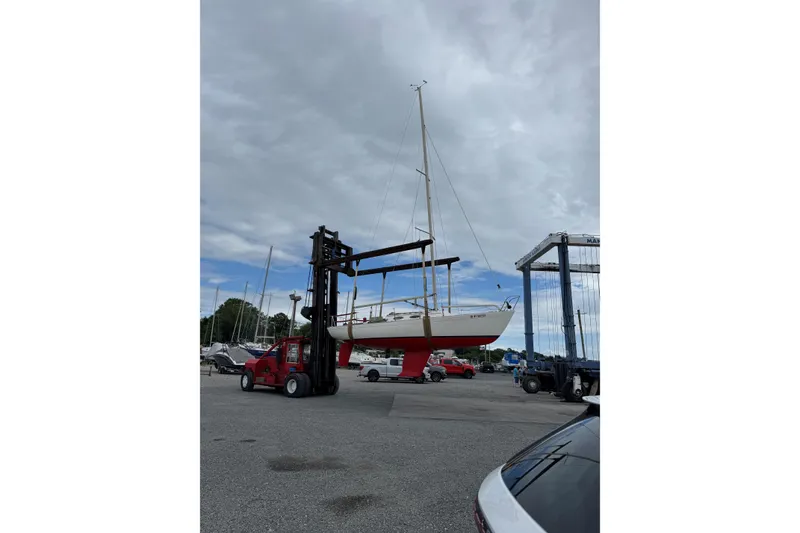 Slide: The Image of 2006 Alerion Express 28 sailboat lifted by forklift in marina. - 11