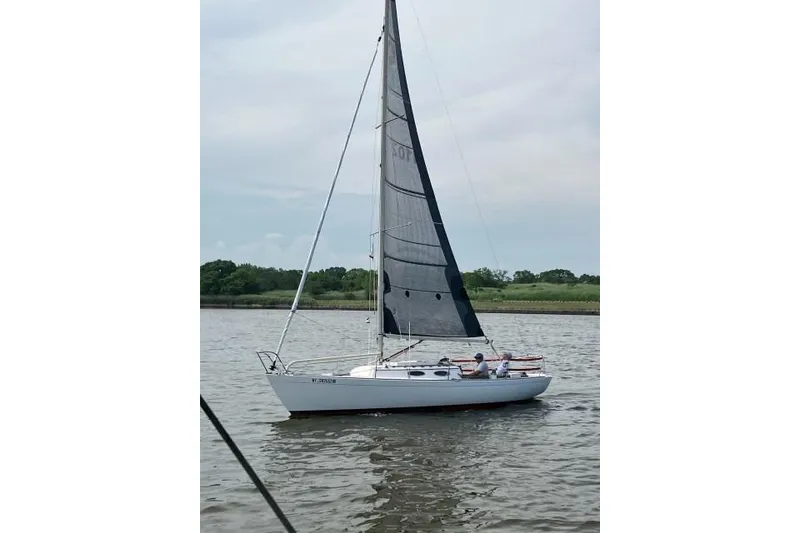 Slide: The Image of 2006 Alerion Express 28 sailboat on calm water with lush green shoreline. - 7