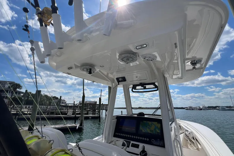 Slide: The Image of 2025 Regulator 28 boat console with fishing rods, under a sunny sky at the marina. - 4