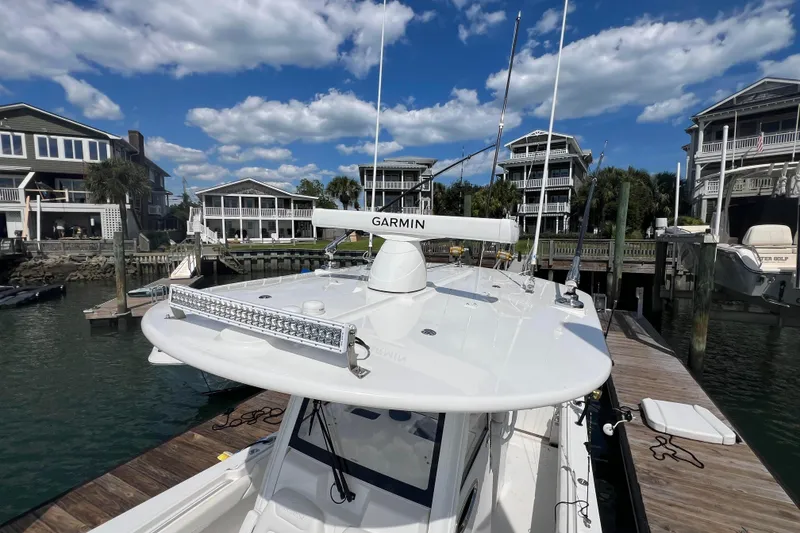 Slide: The Image of 2025 Regulator 28 boat docked at marina with Garmin equipment, under a clear blue sky. - 7