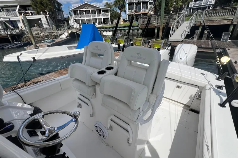 Slide: The Image of 2025 Regulator 28 boat interior with white seating and fishing rods at a dock. - 8