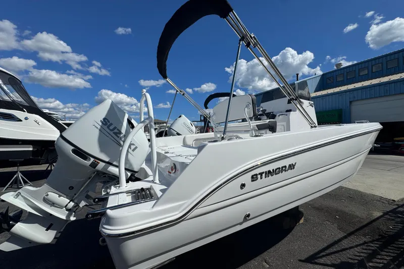 The Image of 2026 Stingray 173 CC boat with Suzuki outboard motor, docked under a clear blue sky. - 1