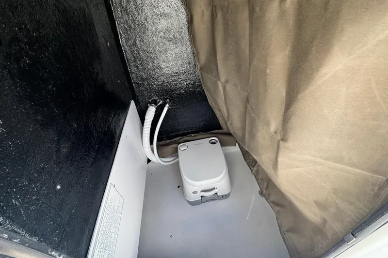 Slide: The Image of 2026 Stingray 173 CC boat interior with portable toilet and privacy curtain. - 19