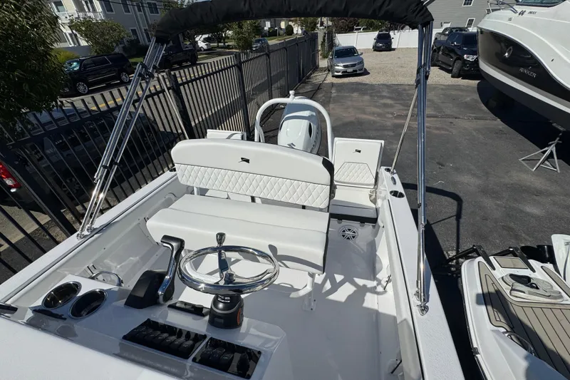 Slide: The Image of 2026 Stingray 173 CC boat interior with steering wheel and seating, parked outdoors. - 21