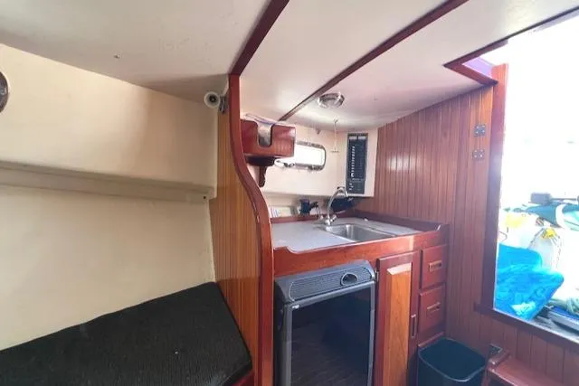 Slide: The Image of Interior of a 2001 Duffy 26 boat featuring a compact kitchen area with wood paneling. - 12