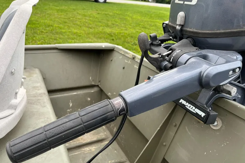 Slide: The Image of 2008 Crestliner CR 1648 boat with outboard motor and steering handle, parked on grass. - 8