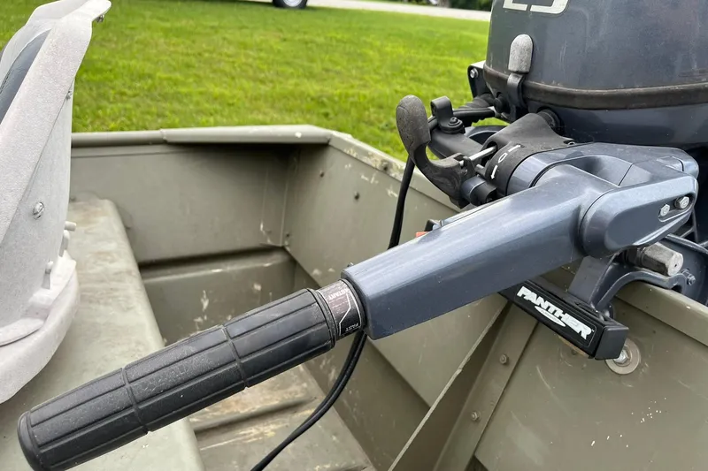 Slide: The Image of 2008 Crestliner CR 1648 boat with outboard motor and steering handle, parked on grass. - 9