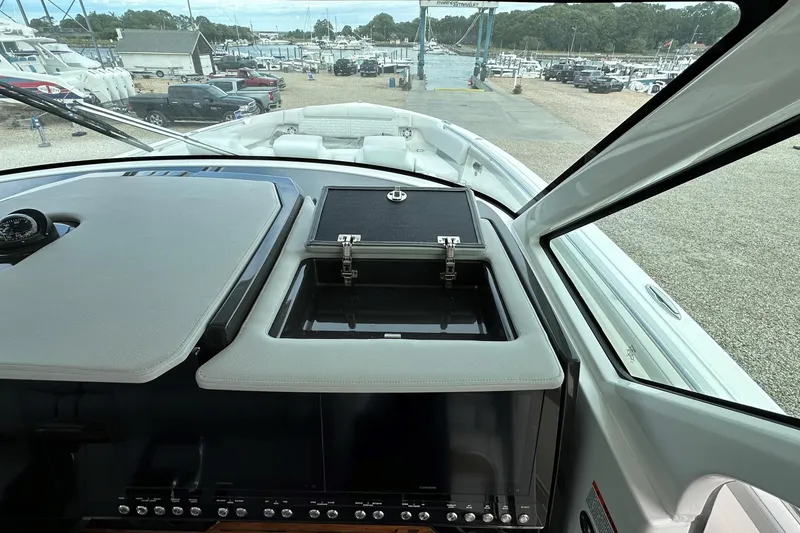 Slide: The Image of 2026 Tiara Yachts 48 LS helm with open storage compartment, marina view in background. - 25