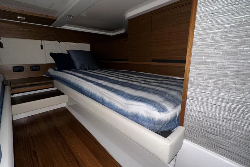 Slide: The Image of 2026 Tiara Yachts 48 LS cabin with modern wood paneling and striped bedding. - 39