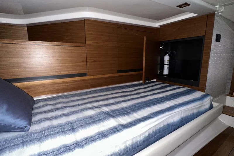 Slide: The Image of 2026 Tiara Yachts 48 LS cabin interior with wooden cabinetry and striped bedding. - 42