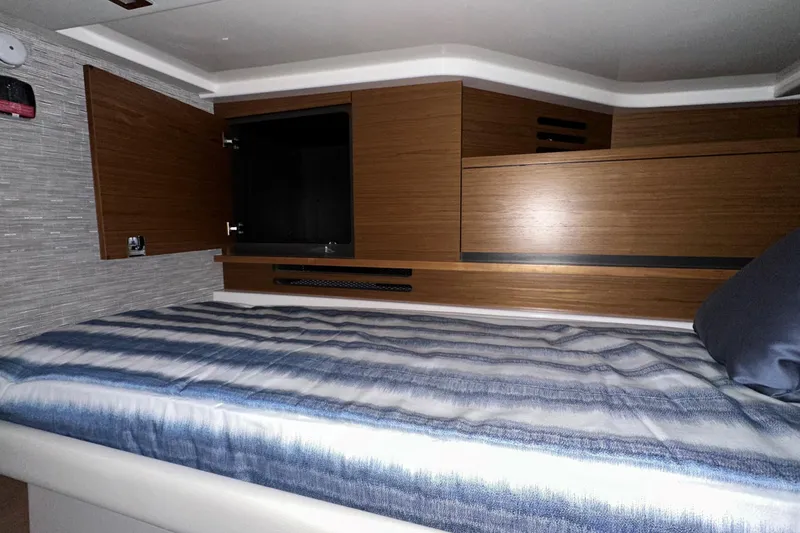 Slide: The Image of Interior cabin of 2026 Tiara Yachts 48 LS with wood paneling and striped bedding. - 43