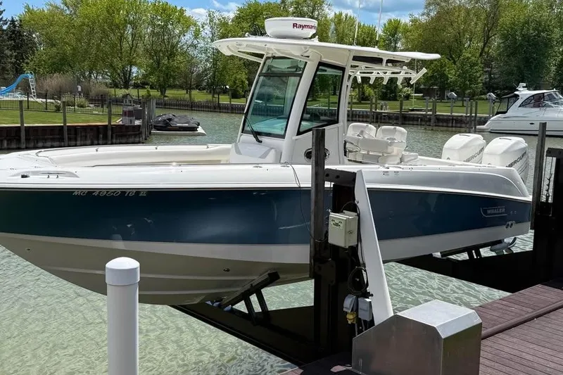Slide: The Image of 2015 Boston Whaler 280 Outrage boat docked on a lift, surrounded by greenery. - 0