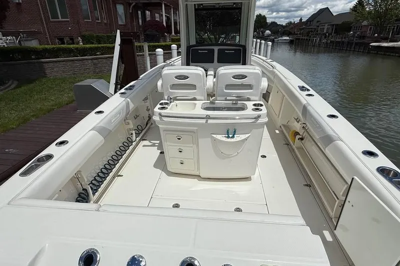 Slide: The Image of 2015 Boston Whaler 280 Outrage boat interior with seating and storage, docked by a canal. - 10