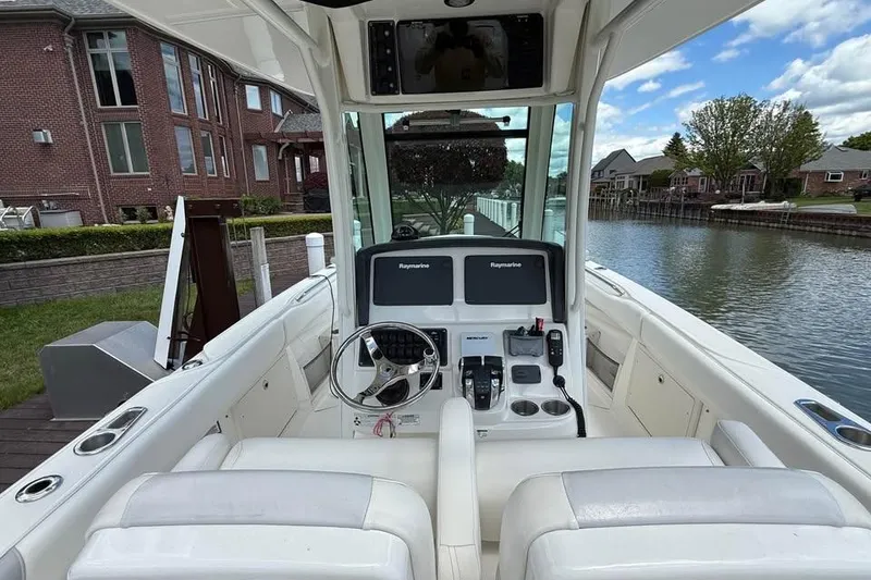 Slide: The Image of 2015 Boston Whaler 280 Outrage boat cockpit with dual Raymarine displays, docked by waterfront homes. - 12