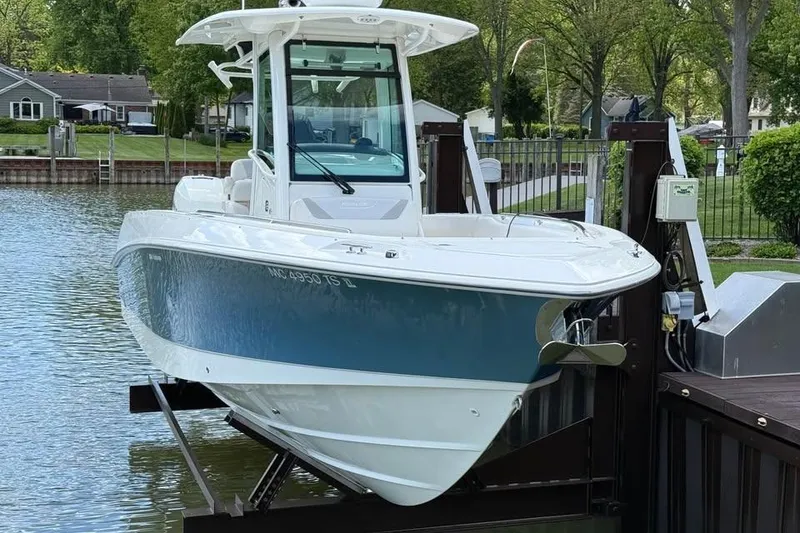Slide: The Image of 2015 Boston Whaler 280 Outrage boat docked by a lakeside, surrounded by greenery. - 2